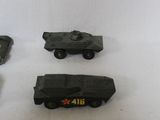 four toy army vehicles are lined up on a white surface