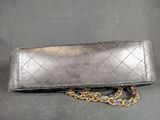 a black purse with a chain around it sitting on a table