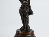 une vieille statue en bronze représentant une femme tenant une bouteille