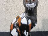 a black and orange cat statue sitting on a black surface