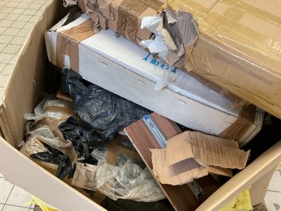une boîte en carton remplie de boîtes et d'autres objets, posée par terre
