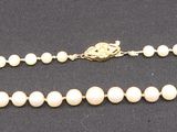 an image of a white beaded necklace on a black surface