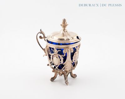 une tasse ancienne, argentée et bleue, avec un couvercle, posée sur un socle