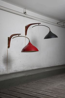 two red and black lamps hanging on a wall next to a wooden floor