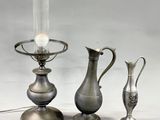 three silver vases and a lamp on a table