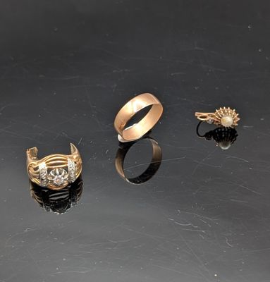 trois bagues en or et une bague ornée d'une perle sur un fond noir