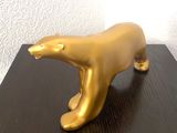 une statue en or représentant un ours polaire, posée sur une table en bois