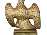 a gold eagle statue on a pedestal with a sign