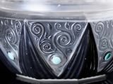 a silver and blue bowl on a black surface