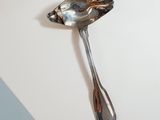 a silver spoon with a bird on it sitting on a table