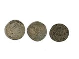 trois pièces romaines, dont l'une porte une tête et l'autre un visage