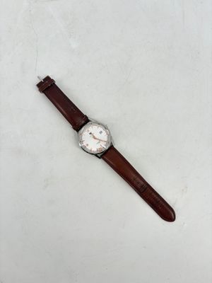 gros plan d'une montre sur une surface blanche avec un bracelet marron