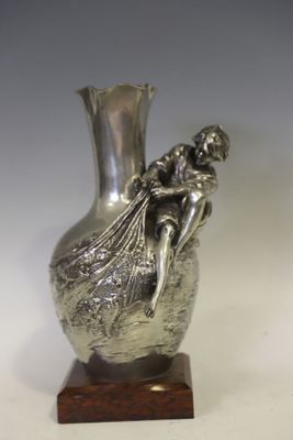 un vase en argent posé sur un socle en bois, sur fond blanc