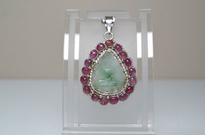 un pendentif serti d'une pierre verte, présenté dans une vitrine transparente