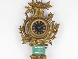 a gold clock on the wall with a green glass