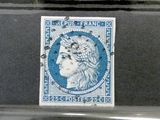 quatre timbres différents sont exposés dans une vitrine posée sur une table
