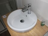 a white sink sitting on a wooden counter in a bathroom