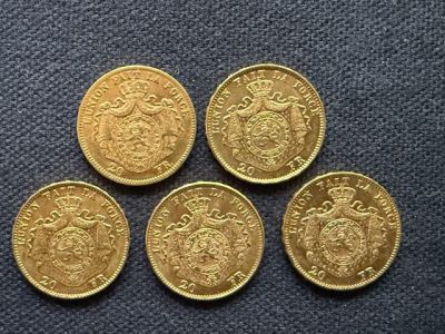 four gold sovereigns sitting on top of each other on a blue surface
