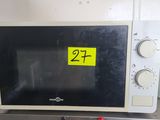 un micro-ondes sur lequel est collé un autocollant jaune, posé sur un plan de travail