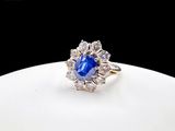 a close up of a blue sapphire and diamond ring on a white plate