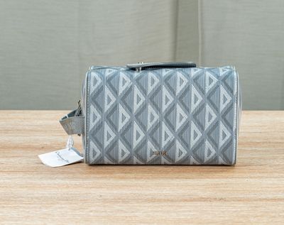 the grey and white cosmetic bag is sitting on a wooden table