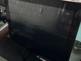 a flat screen tv sitting on top of a shelf in front of a window