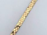 a close up of a gold bracelet on a white surface