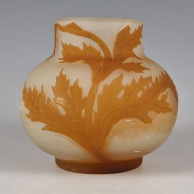 a glass vase with a design of leaves on it