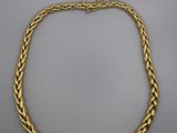 un collier en or avec un motif tressé sur fond blanc
