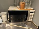 a microwave that is sitting on a counter next to cups