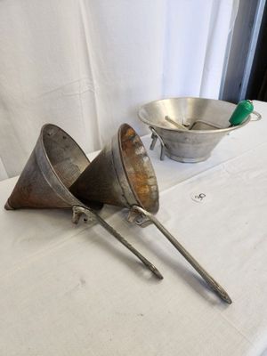 two metal funnels sitting on a table with a bowl in the background