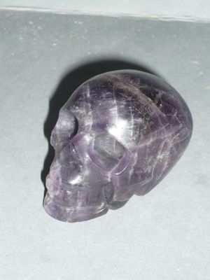 a purple crystal skull sitting on a white surface