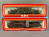 deux boîtes contenant des trains miniatures, posées l'une à côté de l'autre sur une table