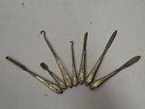 six cuillères et un couteau anciens en argent, posés sur un plateau blanc