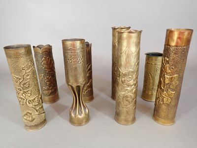 six brass vases are lined up in a row on a white surface