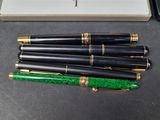 three fountain pens and a box of pens on a table