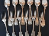 eight silverplated forks and spoons are lined up on a black surface