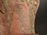 a close up of a brown boot with green stones on it