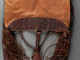 an old purse with fringes hanging on a wall next to a mirror