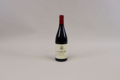 une bouteille de vin rouge posée sur une table blanche