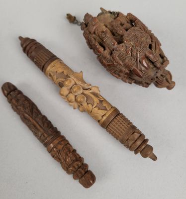 trois objets en bois sculpté posés sur une surface blanche, dont un stylo et un stylo à bille
