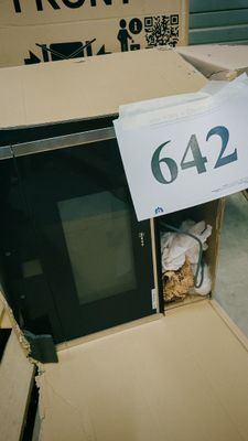un micro-ondes placé à l'intérieur d'un carton sur lequel est apposée une étiquette de prix