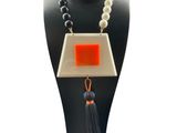 a close up of a necklace on a mannequin with a tassel