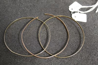 un gros plan sur trois boucles d'oreilles en anneau dorées posées sur une table