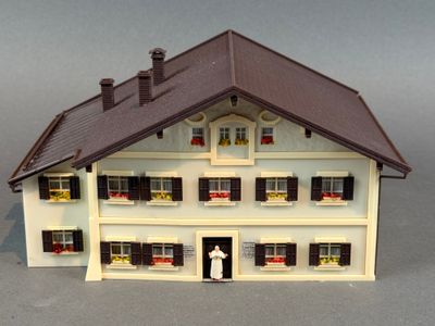 une petite maison de poupées avec un homme debout sur le seuil
