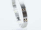 a close up of a silver and gold bracelet on a clear stand