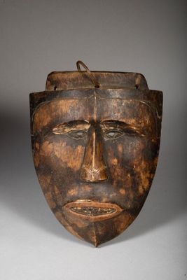 a close up of a wooden mask on a white surface