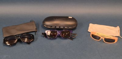 a pair of sunglasses, a case, and a pair of glasses on a blue surface