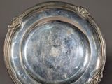 an antique silver plate on a stand on a gray background