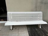 a white bench sitting on a sidewalk next to a building